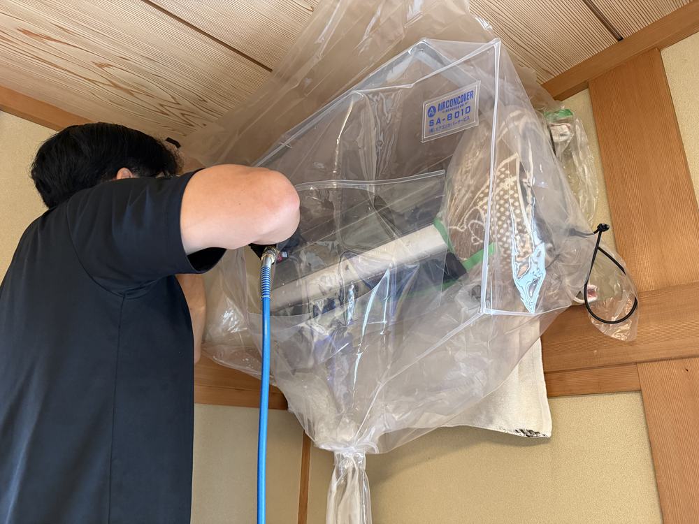 高圧洗浄機のノズルでエアコン内部の熱交換器を洗浄している様子